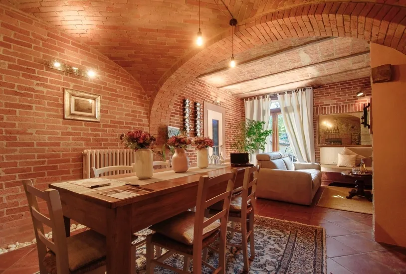 Dining room of renovated old apartment with exposed brick walls, a wooden table with white chairs